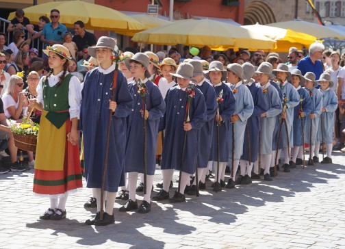 die Schulkinder führen in traditionellen Kostümen historische Tänze auf